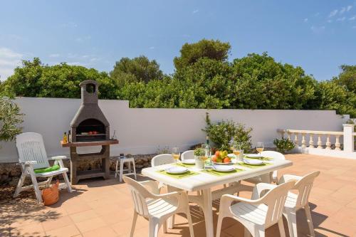 a patio with a table and chairs and a fireplace at Villa CLAUDIA Menorca in Cala'n Porter