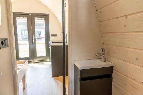 a small bathroom with a sink and a door at Boslodges Veluwe in Nunspeet