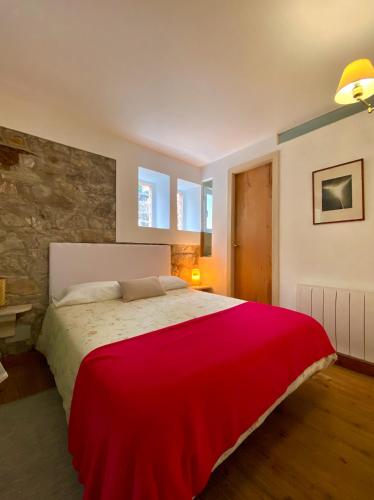 ein Schlafzimmer mit einem großen Bett und einer roten Decke in der Unterkunft La Ventanita Del Campo in La Cavada
