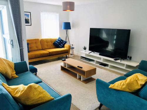 een woonkamer met twee blauwe banken en een flatscreen-tv bij Colonels House in Sandown