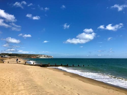 a beach with a group of people in the ocean at Colonels House-Stylish Seafront Townhouse overlooking Sandown Bay in Sandown