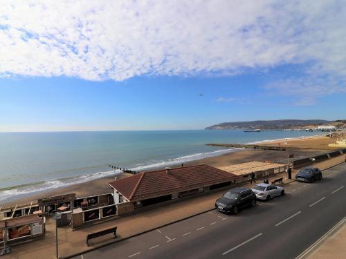 a road with cars parked next to a beach at Colonels House-Stylish Seafront Townhouse overlooking Sandown Bay in Sandown