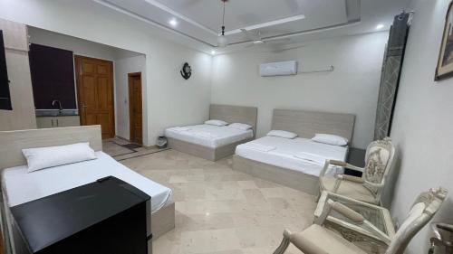 a room with two beds and a desk and a chair at Midways Guest House and Hotels in Islamabad
