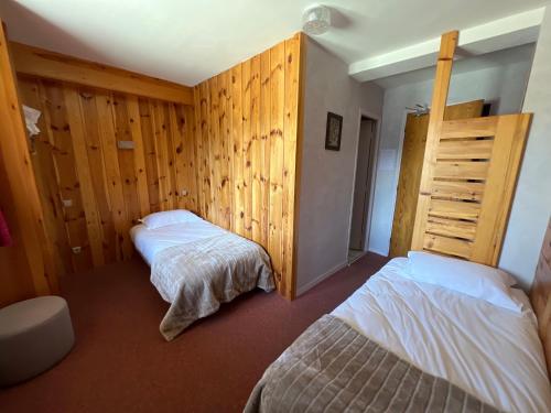 a bedroom with two beds and wooden walls at Hôtel Restaurant La Pendine in Puy-Saint-Vincent