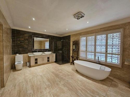 uma grande casa de banho com banheira e 2 lavatórios em Arum Lily Eloff em Delmas