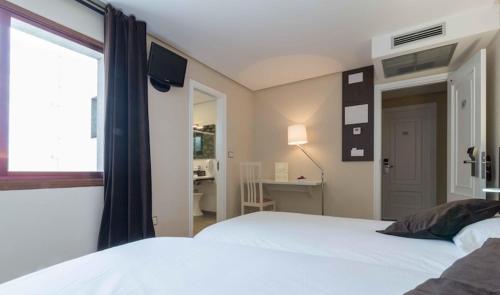 a bedroom with a bed and a desk and a window at Hotel Mogay in Chantada