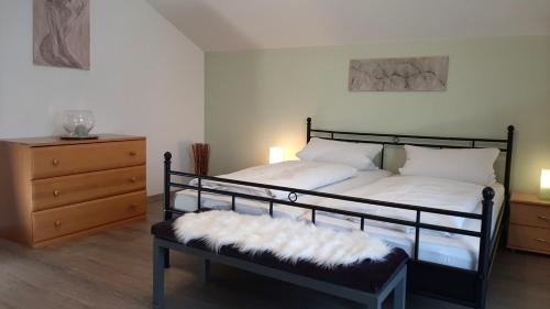 um quarto com uma cama com um banco e uma cómoda em Ferienwohnungen Geier em Niederalteich