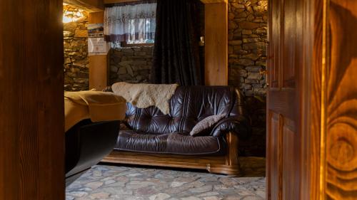 a brown leather couch in a room with a stone wall at Jaworowa Osada in Brenna