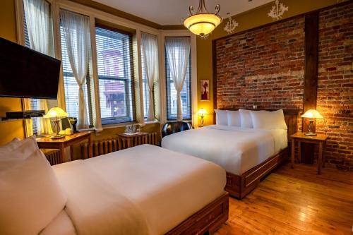 a hotel room with two beds and a brick wall at Hotel Ermitage in Quebec City