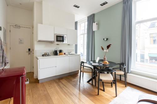 a kitchen with white cabinets and a table with chairs at Numa Amsterdam Helmers in Amsterdam