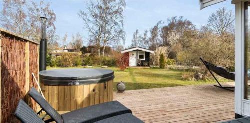 Cozy Cottage With Wilderness Bath في Føllenslev: سطح مع حوض استحمام ساخن وكراسي على الفناء