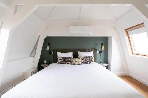a bedroom with a white bed with a green headboard at Yays Amsterdam Vondelpark by Numa in Amsterdam