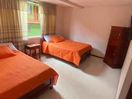 a hotel room with two beds and a window at Hotel Paucura in Pácora