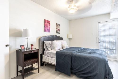 a bedroom with a bed and a table with a night stand at COZY LONG TERM APT WITH POOL ACCESS IN DFW in Dallas