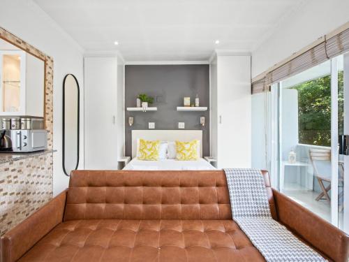 a bedroom with a brown leather couch and a bed at Fairmile Urban Oasis in Cape Town