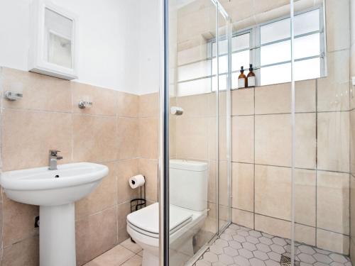 a bathroom with a toilet and a glass shower at Fairmile Urban Oasis in Cape Town