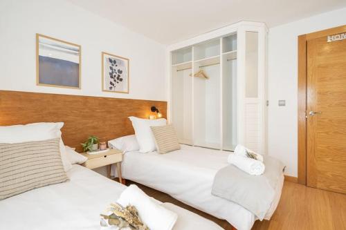 2 bedden in een hotelkamer met witte lakens bij Escalera 12 in Gijón