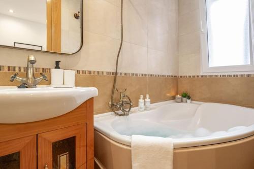 een badkamer met een wit bad en een wastafel bij Escalera 12 in Gijón