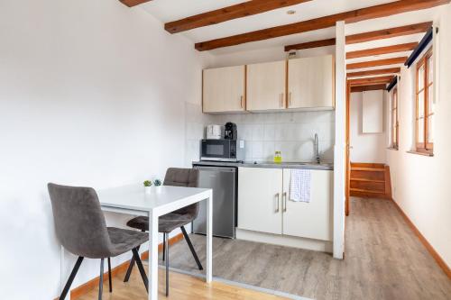 une petite cuisine avec une table et des chaises blanches dans l'établissement Travel Homes - Tanneur 6, heart of Petite Venise, à Colmar