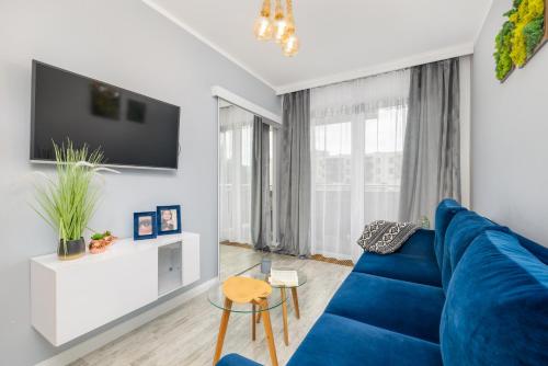 een woonkamer met een blauwe bank en een tv bij Kapitański Mostek Pet-Friendly Apartment Kołobrzeg by Renters in Kołobrzeg