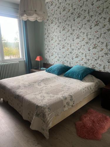 a bedroom with a bed with blue pillows on it at Chambre dans jolie nature in Auxi-le-Château
