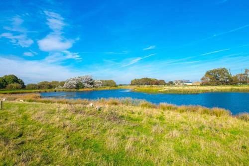 MP39 Parkdean Camber Sands في Camber: نهر في حقل مع السماء الزرقاء
