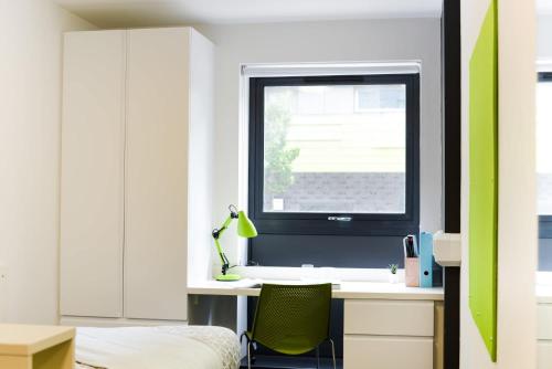 Cette chambre comprend un bureau avec une fenêtre et une chaise verte. dans l'établissement Stylish Studios and Ensuites Steps from Newcastle University at St James Point, à Newcastle upon Tyne