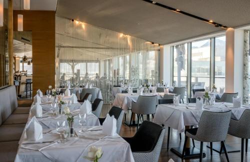 a restaurant with tables and chairs with white tablecloths at IMLAUER HOTEL PITTER Salzburg in Salzburg