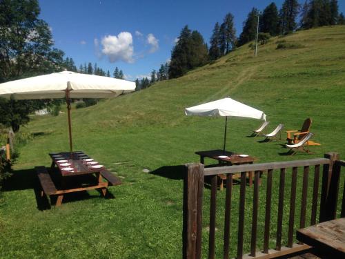 two tables and chairs with umbrellas on a hill at Agriturismo il Fiocco in Cesana Torinese