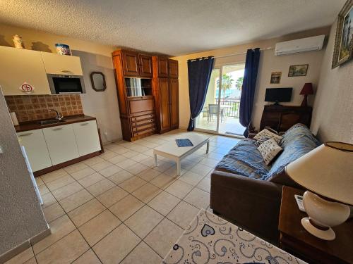 un salon avec un canapé et une cuisine dans l'établissement Palmeraie 136- Vue mer- piscine en résidence, à Sari-Solenzara