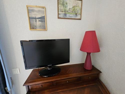 une télévision sur une table en bois avec une lampe rouge dans l'établissement Palmeraie 136- Vue mer- piscine en résidence, à Sari-Solenzara