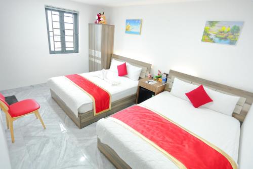 a bedroom with two beds and a red chair at SKY HOTEL in Long Thành