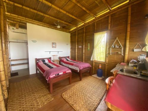 twee bedden in een kamer met houten wanden bij Bungalows Ayampe in Ayampe