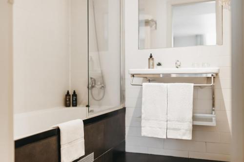 a bathroom with white towels and a sink and a shower at Oriente Atiram in Barcelona