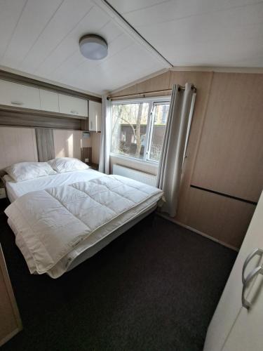 een slaapkamer met een bed en een raam bij Ruim Chalet, midden in het bos! in Nunspeet