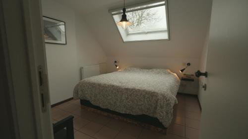 a small bedroom with a bed and a window at Gastenverblijf 't Hof van Eden in Wingene