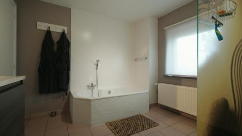 a bathroom with a bath tub and a shower at Gastenverblijf 't Hof van Eden in Wingene