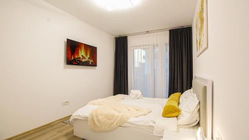 - une chambre avec un lit doté de draps blancs et d'oreillers jaunes dans l'établissement MO Apartment One, à Braşov