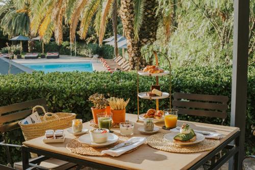 a table with food and drinks on it next to a pool at Mas de Torrent Hotel & Spa, Relais & Châteaux in Torrent