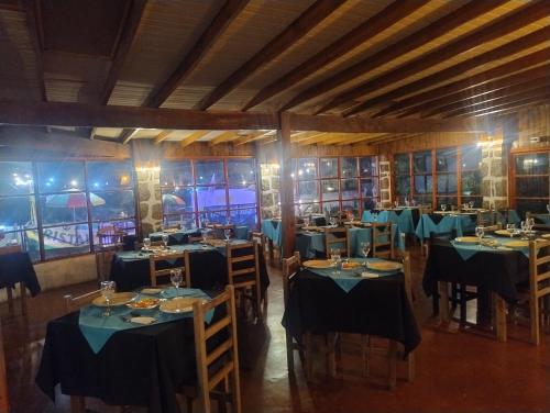 a dining room with blue tables and chairs and windows at Hotel Brisas del Quisco in El Quisco