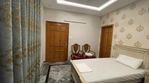 a bedroom with a bed and two chairs at Midways Guest House and Hotels in Islamabad