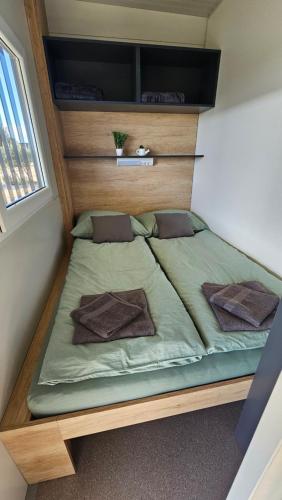 ein großes Bett in einem kleinen Zimmer mit Fenster in der Unterkunft CHARTA mobile home Nada in Pirovac