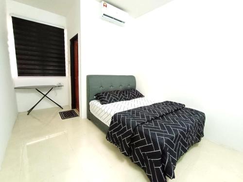 a bedroom with a bed with a black and white comforter at Indera Sempurna Ruma Aisya in Kuantan