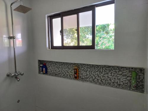 ein Bad mit einem Fenster, einem Waschbecken und einem Spiegel in der Unterkunft Ika homes in Nyali
