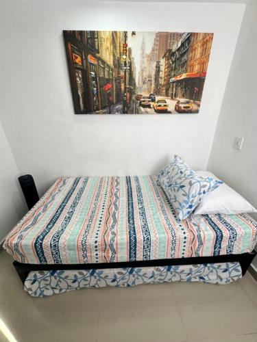1 cama en una habitación con una foto en la pared en Amplio ApartaStudio en Boston, en Medellín