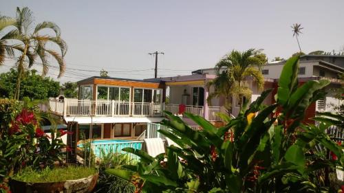 ein großes Haus mit einem Balkon und Palmen in der Unterkunft Gites cœur des Antilles in Trois-Rivières