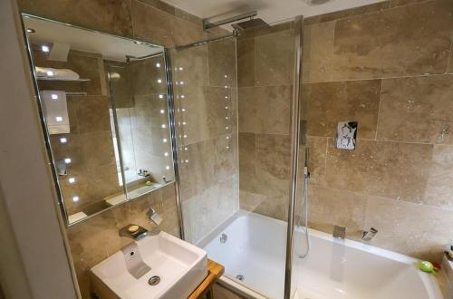 a bathroom with a shower and a tub and a sink at The Cheviot Hotel in Bellingham