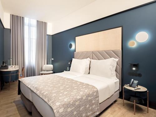 a bedroom with a large bed and a blue wall at Axis Porto Club Aliados in Porto