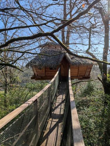 a tree house with a roof on a bridge at Les hébergements insolites de Quénécan in Perret