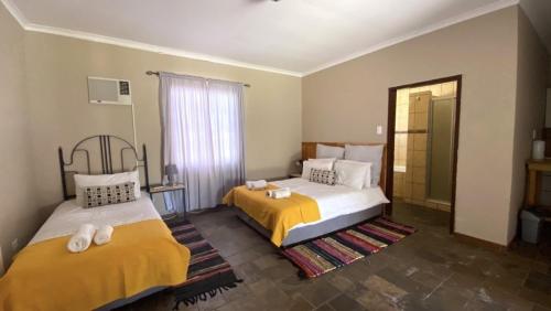 Habitación de hotel con 2 camas y ventana en Stoney's Country Hotel en Gochas